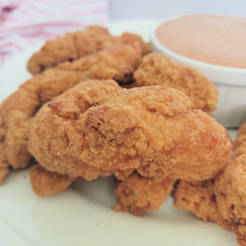 Air fried chicken tenders on a white plate with dipping sauce