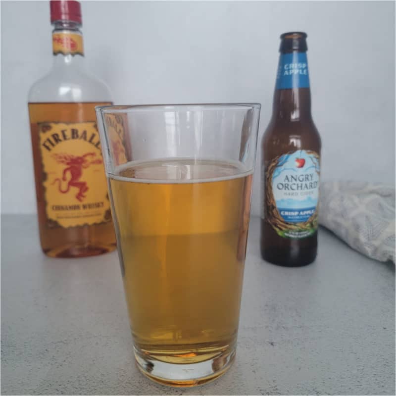 Angry Balls Drink in a tall glass in front of a bottle of fireball and angry orchard hard cider