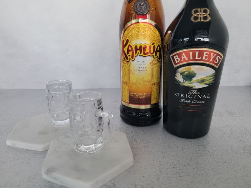 Baby Guinness Shot ingredients, Kahlua and Baileys next to 2 mini beer glasses
