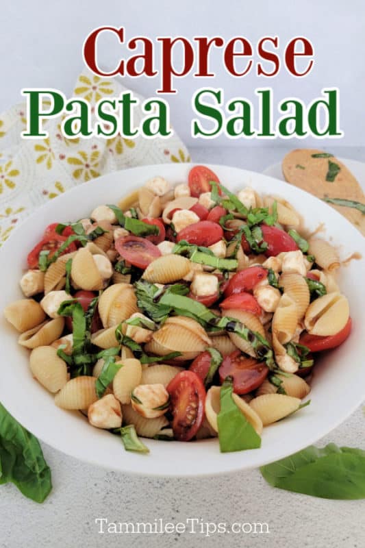 Caprese Pasta Salad text over a white plate with pasta shells, tomatoes, mozzarella, and basil strips next to a wooden spoon and cloth napkin