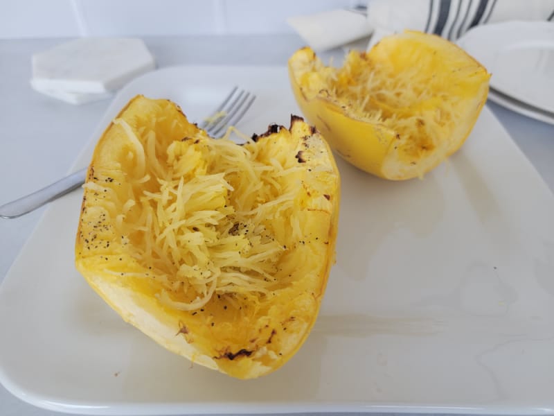 air fryer spaghetti squash next to a fork on a white plate. 