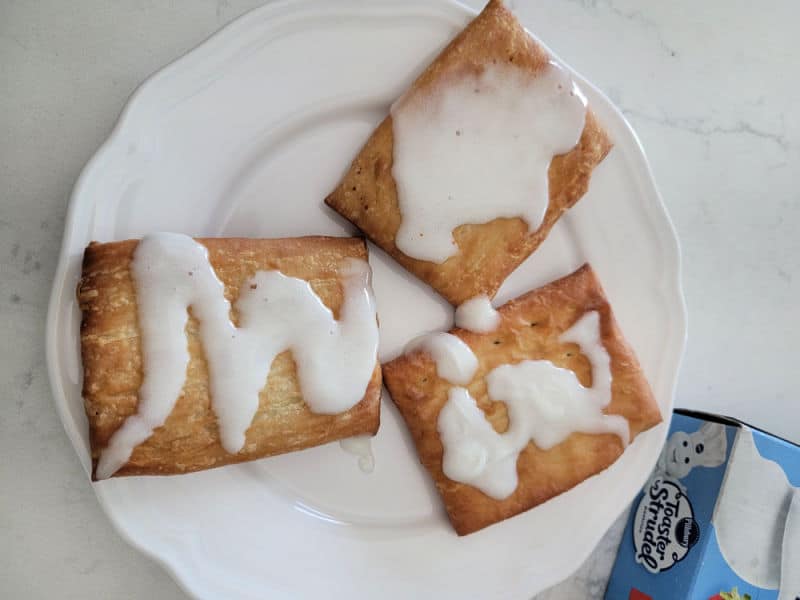 air fried toaster strudel on a white plate near a box of toaster strudels. 