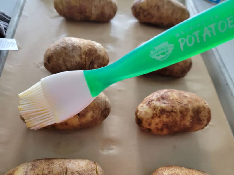 butter brushing onto hasselback potatoes