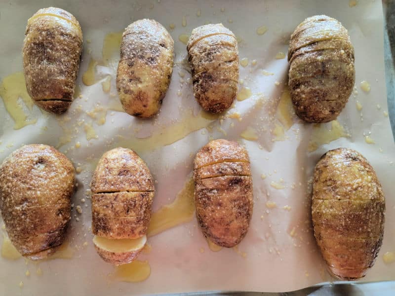 oil and salt covered hasselback potatoes on parchment paper