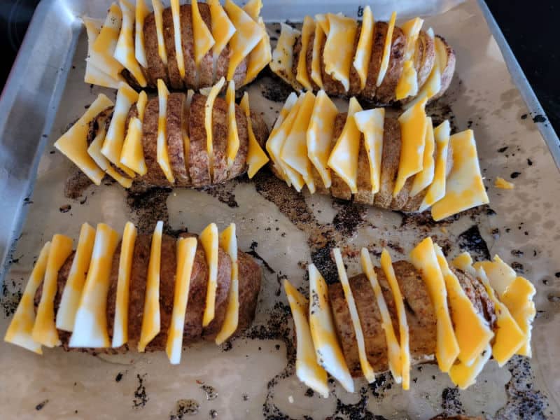 cheese slices in hasselback potatoes on parchment paper