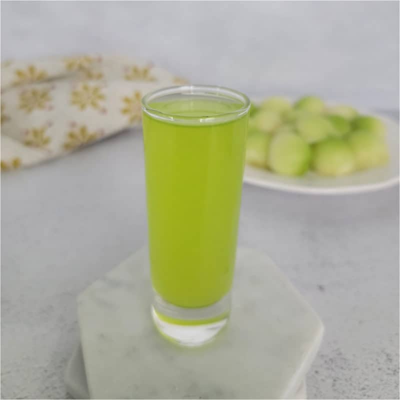 Melon Ball Shot on a white coaster next to a plate of melon