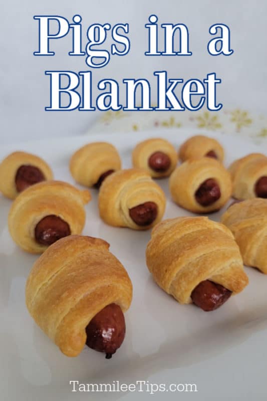 Pigs in a blanket over sausages wrapped in dough lined on a white platter