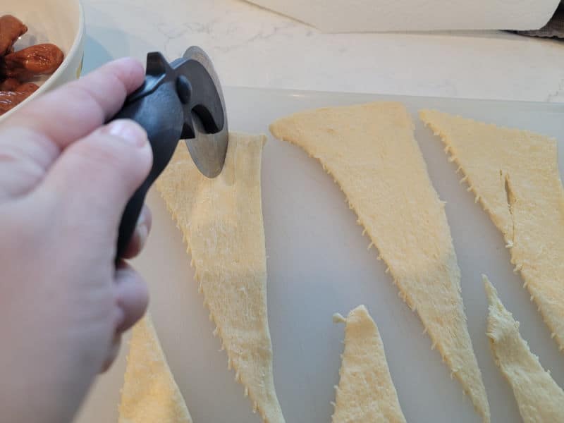 Pizza cutter cutting crescent dough down the middle