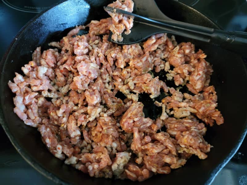 Italian sausage in a cast iron skillet with a mix n chop