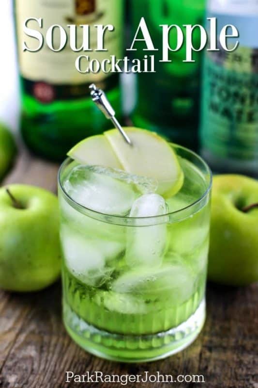 Sour apple cocktail text over a bright green drink with apple slices