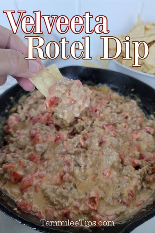 Velveeta Rotel Dip over a hand holding a tortilla chip with dip on it above a cast iron skillet filled with dip 