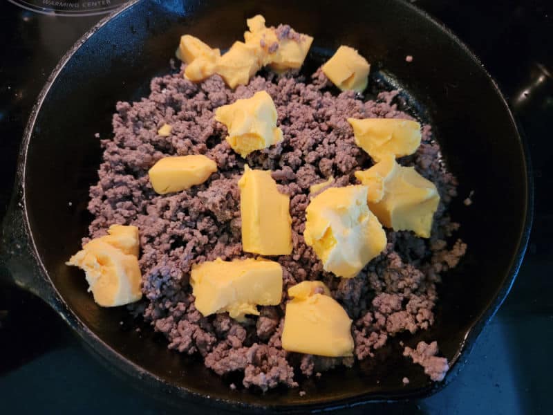 Velveeta cubes and ground beef in a cast iron skillet