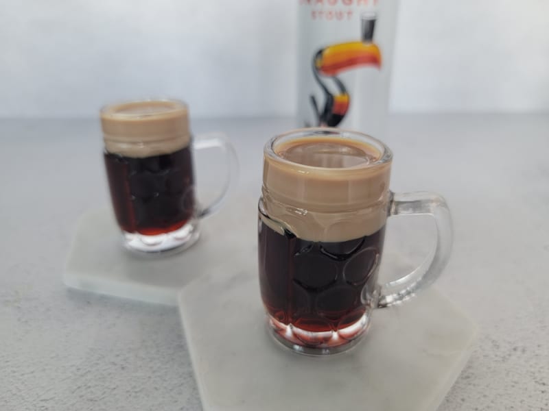 2 Baby Guinness Cocktail Shooters in mini beer glasses on white coasters