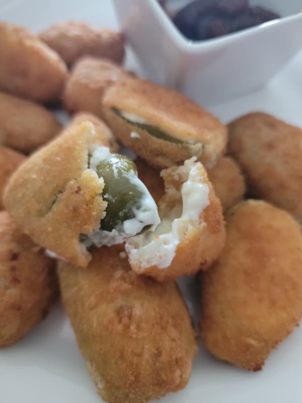 a plate of jalapeno poppers with one split open. 