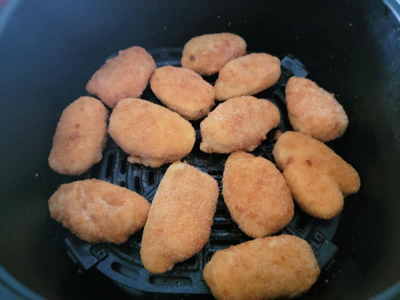 Frozen jalapeno poppers in an air fryer basket