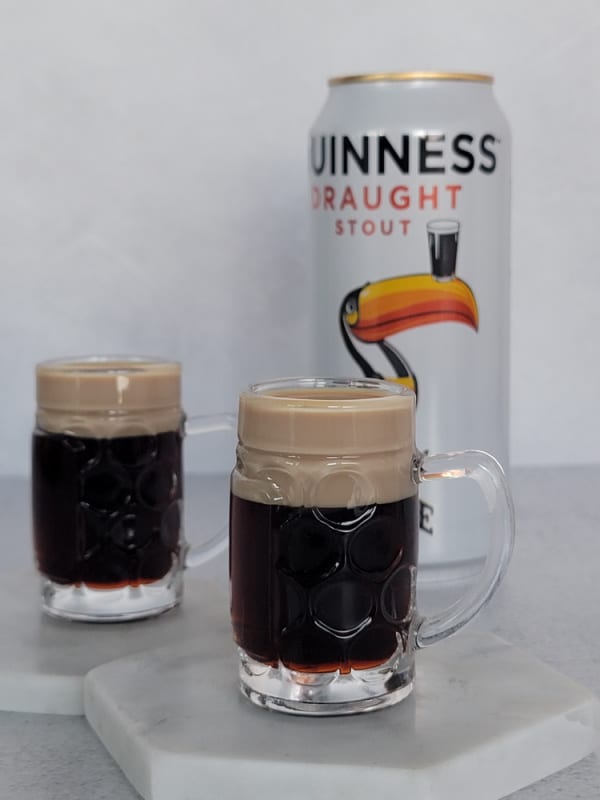 2 Baby Guinness Shots in mini beer glasses next to a can of Guinness