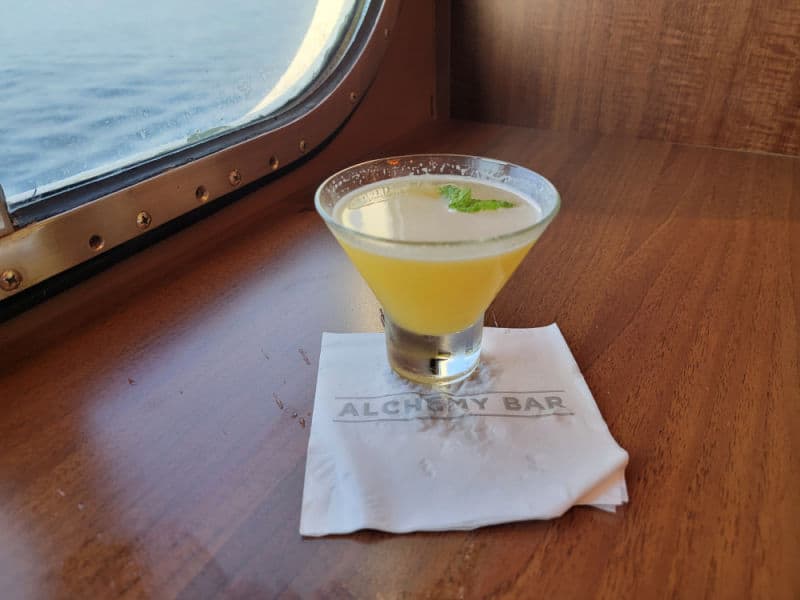 Spicy Chipotle Martini on an Alchemy Bar napkin with the ocean in the background 