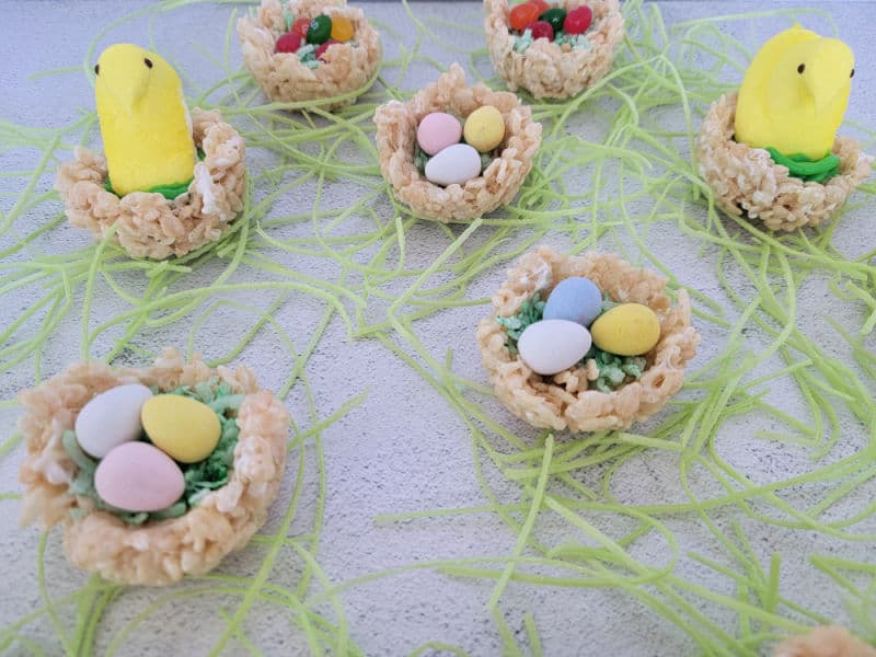 Rice Krispie nests with coconut grass, chocolate eggs, and peeps surrounded by edible grass