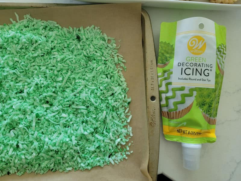 Coconut grass on a baking sheet next to Wilton green icing