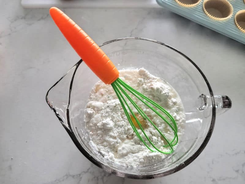 Carrot whisk in batter in a glass bowl 