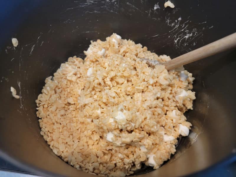 Rice Krispies in a pot with marshmallows and a wooden spoon