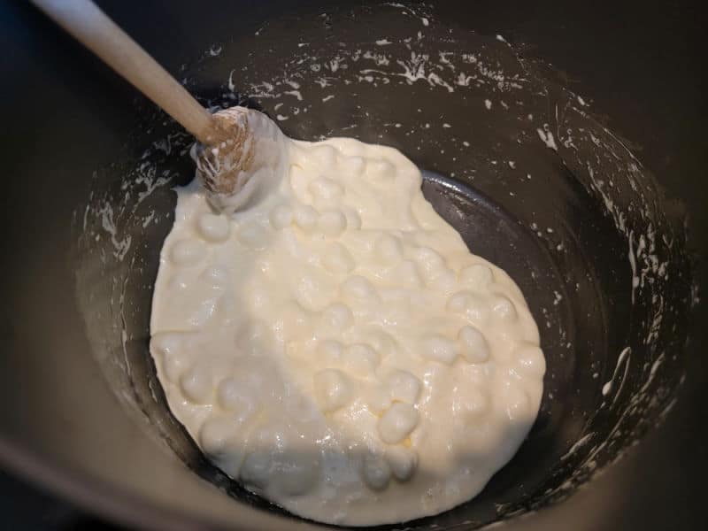 Marshmallows melting in a pot with a wooden spoon