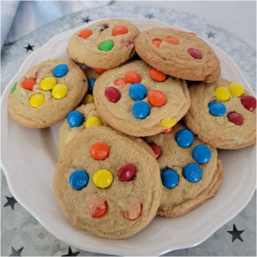 M&M cookies stacked on a white plate on a silver platter with stars