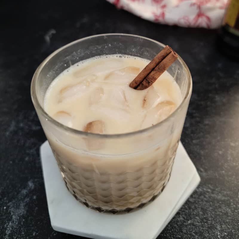 Eggnog White Russian in a crystal glass garnished with a cinnamon stick