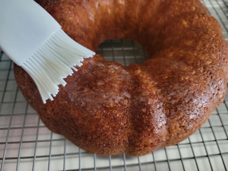 spreading glaze on an apple cider donut cake