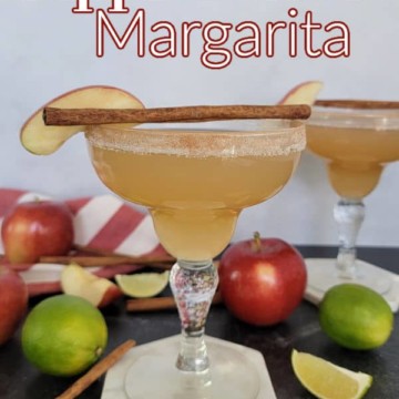 Apple Cider Margarita text printed over a cinnamon sugar rimmed margarita glass with cinnamon stick and apple slice garnish