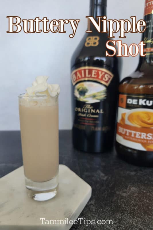 Buttery nipple shot in a tall shot glass next to a bottle of Irish cream and butterscotch schnapps