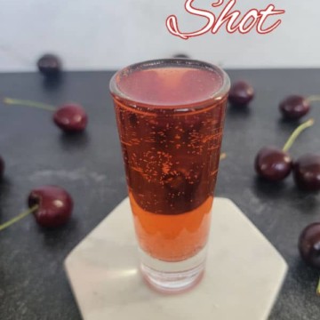 cherry bomb shot text printed over a filled shot glass surrounded by cherries