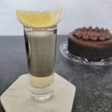 Chocolate cake shot with lemon garnish next to a chocolate cake