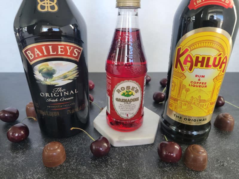 Baileys Irish Cream, Grenadine, and Kahlua bottles next to chocolate covered cherries