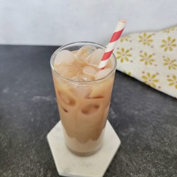 Easy Iced Chai Tea Latte in a tall glass with a red striped straw