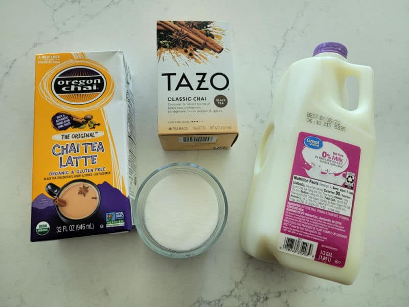 Oregon Chai Latte box, Tazo Classic Chai box, milk, and sugar on a white counter 