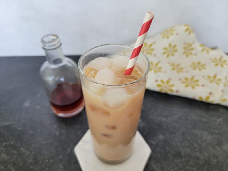 Iced chai in a tall glass with a striped straw