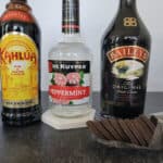 Kahlua, Peppermint Schnapps, and Baileys Irish Cream bottles next to a sleeve of Thin Mint Cookies