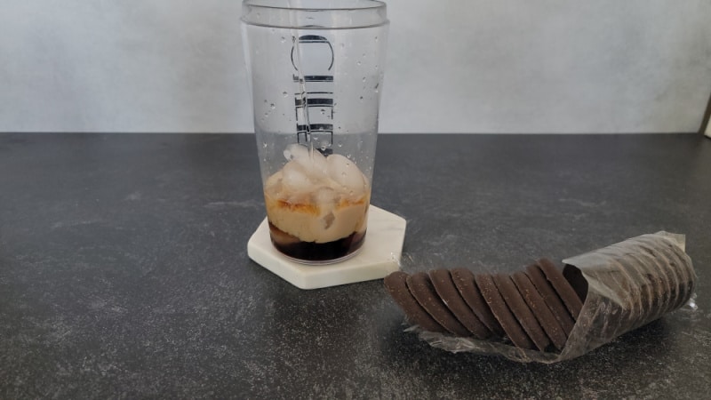 Clear liquid pouring into a cocktail shaker next to a sleeve of thin mint cookies