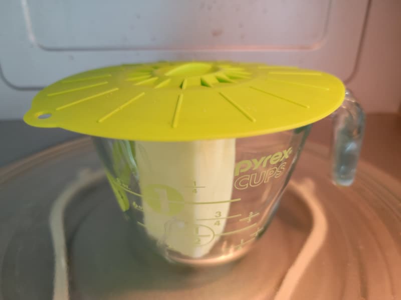splatter cover on a measuring cup with butter in the microwave