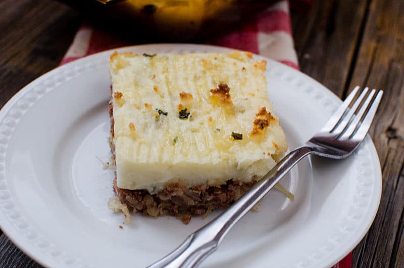 square piece of corned beef shepherd's pie on a white plate with a fork