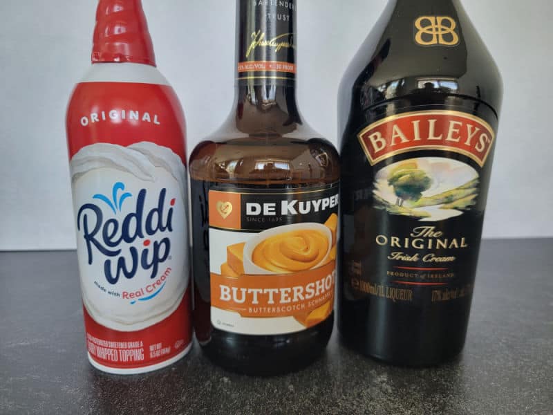 Reddi Whip can, Buttershots, and Baileys Original Irish Cream bottle lined up together