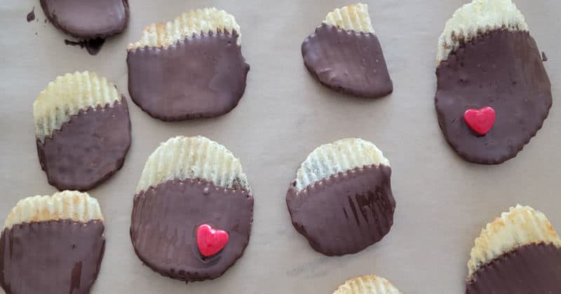 Potato chips dipped in chocolate spread on parchment lined baking sheet