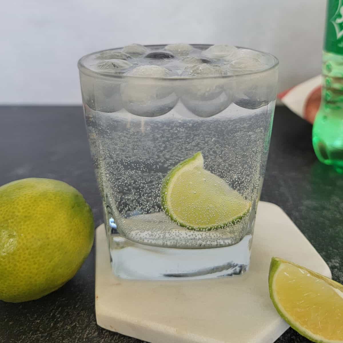 Vodka and Sprite Cocktail with a lime wedge on a coaster next to a lime