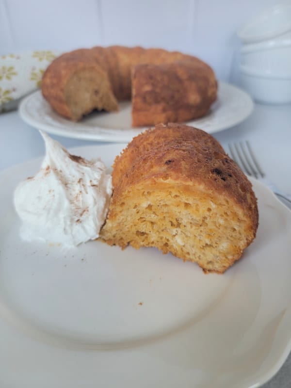 Slice of angel food cake on a white plate with whipped cream