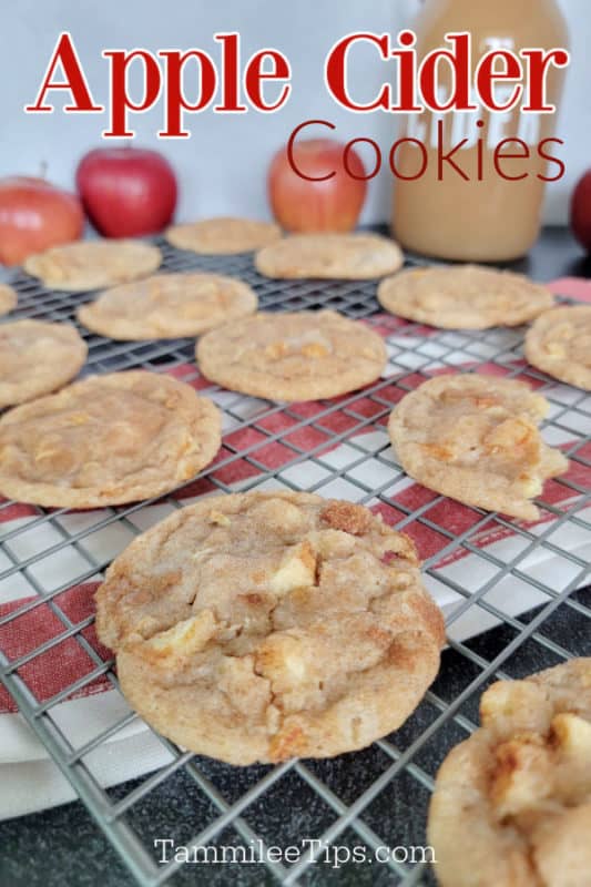 Apple Cider Cookies over a wire rack with cookies, a cloth napkin, and jug of cider with apples in the background