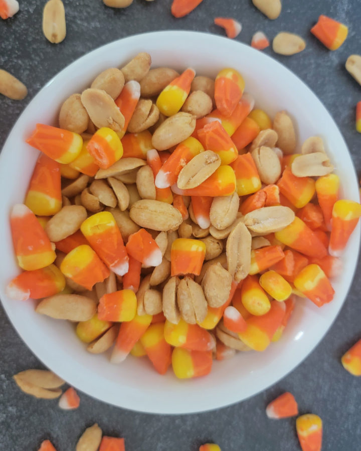 Candy corn and peanuts in a white bowl