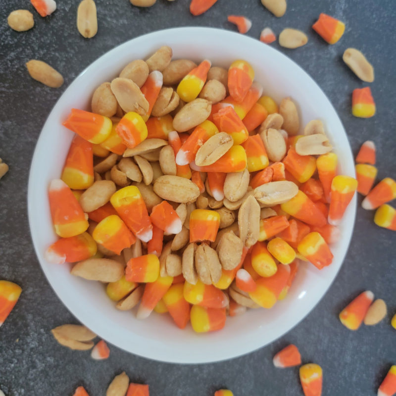Candy corn and peanuts in a white bowl