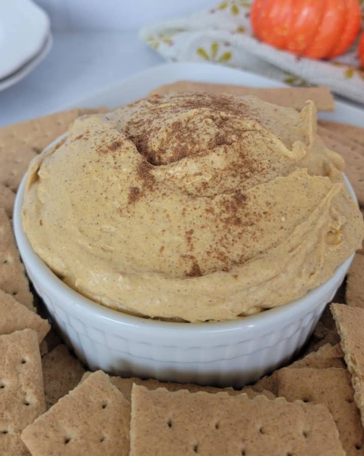 Pumpkin Cream Cheese Dip in a white bowl surrounded by graham crackers
