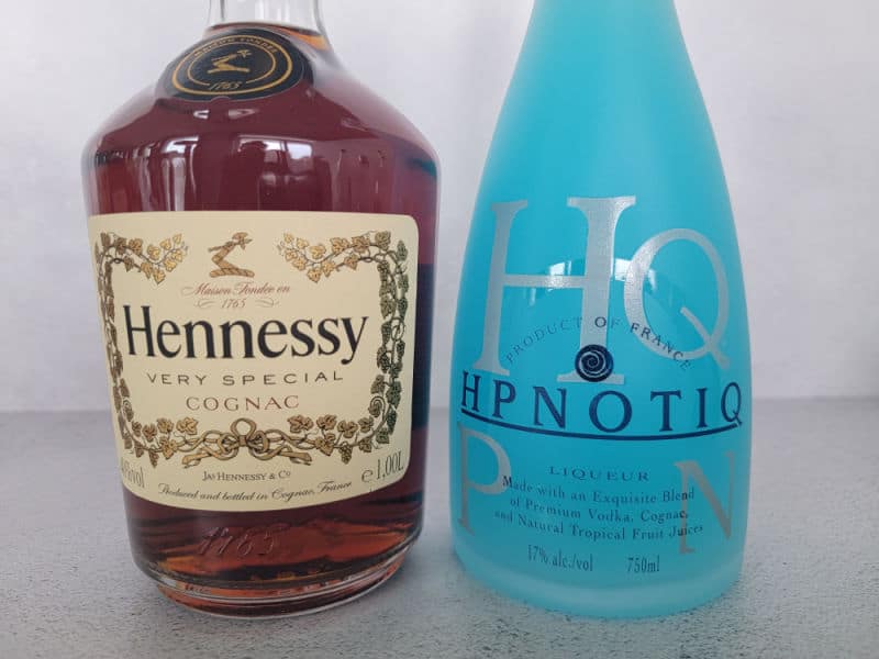 Hennessy very special cognac bottle next to a blue Hpnotiq bottle